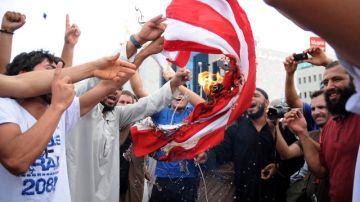 Manifestantes airados queman una bandera de EEUU en represalia por el filme que ridiculiza al profeta.