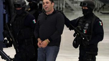 Ramiro Pozos González es todo sonrisas mientras es escoltado por agentes de la  Policía federal en México.