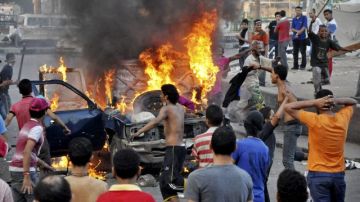 Manifestantes egipcios se reúnen alrededor de un vehículo en llamas en el centro de El Cairo, Egipto, antes que la policía despejara el área después de días de protestas en contra de una película que ridiculiza al profeta Mahoma.