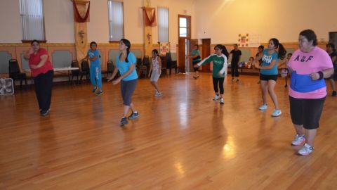Alumnas de la clase de zumba haciendo sus rutinas de ejercicios en el auditorio de Universidad Popular.