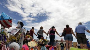Un grupo de personas se toman de las manos y rezan en un memorial el 30 de julio de 2012 en Aurora, Colorado  donde doce personas murieron y más de 50 resultaron heridas en un ataque a tiros el viernes anterior.