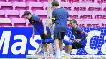 Lionel Messi (izq.) y el brasileño Dani Alves realizan ejercicios de estiramiento en preparación para el encuentro de hoy en casa.