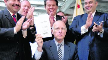 El Gobernador Jerry Brown muestra el documento firmado, rodeado de varios asambleístas y senadores estatales.