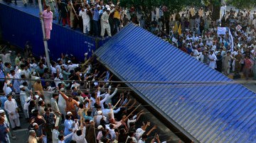 Miles de manifestantes movían un contenedor que usaba  la policía y con ello intentaban bloquear la calle que conduce al consulado de Estados Unidos en Lahore, Pakistán.