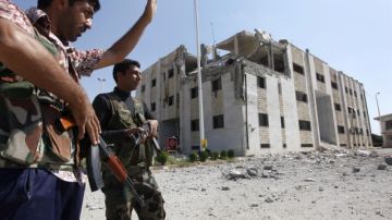 Rebeldes sirios frente al edificio del Departamento de Inmigración destruido en Tal Abyad, un cruce en la frontera turco-siria  capturado por los rebeldes.