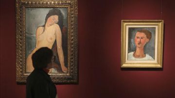 Una mujer contempla dos cuadros del pintor francés Amadeo Modigliani " Mujer sentada" (i) y "Retrato de un joven".
