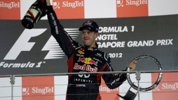 Sebastian Vettel celebra con champaña sosteniendo su trofeo.