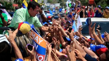 El candidato presidencial de la oposición, Henrique Capriles (izq.), saluda a sus partidarios en acto de campaña, en La Guaira, Venezuela, ayer.