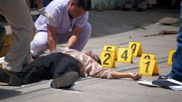 Los trabajadores del Forensic examinan el cuerpo del abogado del distrito Manuel Eduardo Díaz Mazariegos después de que lo dispararan en Choluteca, Honduras, el 24 sept., 2012.