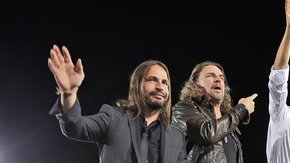 El presidente Barack Obama saluda a la gente acompañado en el estrado de los miembros de la banda mexicana de rock Maná, durante un acto de campaña en la secundaria Desert Pines, el domingo 30 de septiembre de 2012 en Las Vegas.