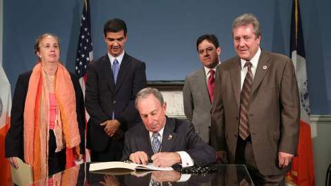 A la izquierda, Ramona Hernández, directora del Centro de Estudios Dominicanos y el concejal Ydanis Rodríguez observan al alcalde de la ciudad de Nueva York, Michael Bloomberg, cuando firma el tributo a Juan Rodríguez.