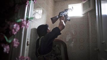 Un insurgente buscaba ayer desde una ventana a militares del régimen de al Asad, con quienes se mantiene una reñida batalla.