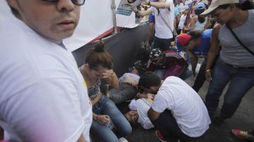Un simpatizante de Capriles yace en el suelo, luego de un enfrentamiento entre chavistas y opositores durante el fin de semana.