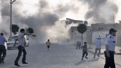Ciudadanos turcos escapan del humo provocado por una bomba de mortero lanzada desde Siria, en Sanliurfa, Turquía, ayer.