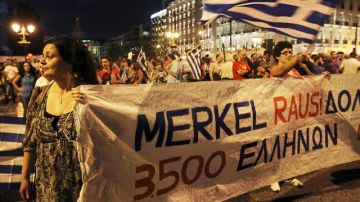 Varias personas sostienen una pancarta en la que se puede leer 'Fuera Merkel', en manifestación celebrada frente al Parlamento griego en Atenas, Grecia.