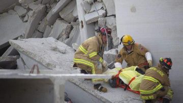 Los bomberos de Miami sacan el cuerpo de una de las víctimas fatales del derrumbe.