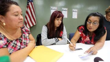 Odilia Romero, del Fondo Indígena, le muestra a Guadalupe Caballero y a su hija Yadira cómo llenar los formularios para solicitar el beneficio de DACA.