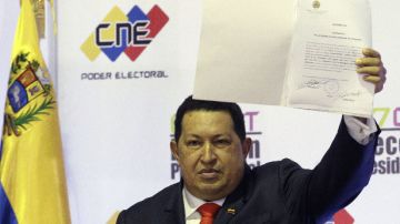 Hugo Chávez sostiene el documento oficial que lo declara ganador de las elecciones en Venezuela.