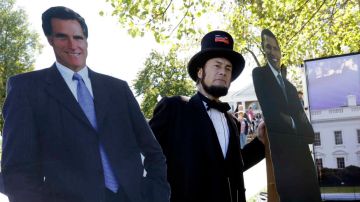 Un actor vestido como Abraham Lincoln posa junto a figuras en cartón de los candidatos a la presidencia Mitt Romney y Barack Obama en Kentucky.