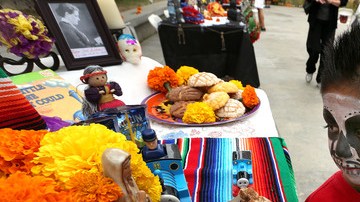 Dos  menores con las caras pintadas miran entretenidos las mesas con los altares levantados por el Día de los Muertos en el Centro del Pueblo, mientras los adultos  aprovechan para inscribirse  para votar.