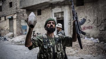 Un miembro del ejército rebelde muestra su armamento en una de las derruidas calles de Alepo, otra de las ciudades más castigadas por los bombardeos de las fuerzas del Gobierno.