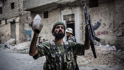 Un miembro del ejército rebelde muestra su armamento en una de las derruidas calles de Alepo, otra de las ciudades más castigadas por los bombardeos de las fuerzas del Gobierno.