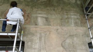Una trabajadora del Getty Conservation Institute restaurando  el área central del polémico mural que ya está abierto al público.