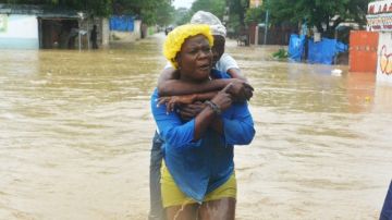 Dos mujeres caminan por una calle inundada  en el municipio de Cité Soleil, en Puerto Príncipe, Haití, donde se registran 29 muertes.
