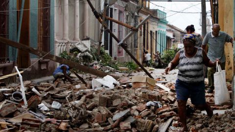 Residentes caminan por sobre los escombros de las casas que fueron dañadas por el huracán Sandy en Santiago de Cuba, el viernes.