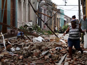 Residentes caminan por sobre los escombros de las casas que fueron dañadas por el huracán Sandy en Santiago de Cuba, el viernes.