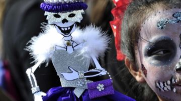 Una niña disfrazada de catrina sostiene una muñeca en Monterrey, México, donde la fiesta comenzó el  27 de octubre.