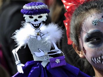 Una niña disfrazada de catrina sostiene una muñeca en Monterrey, México, donde la fiesta comenzó el  27 de octubre.