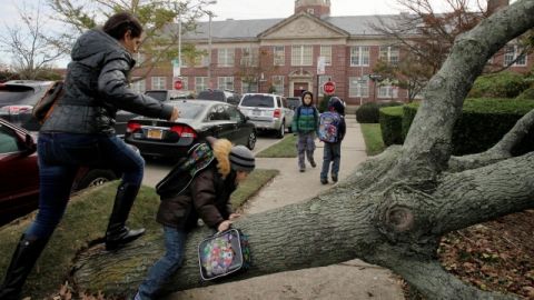 Una mujer y su hijo pasan por encima de un árbol para llegar hasta la escuela pública 195, en Manhattan Beach, Brooklyn, ayer.
