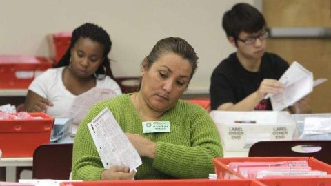 Cynthia Salinas, centro, procesa una boleta enviada por correo en el Registro del Condado de Sacramento de Votantes en Sacramento, California.