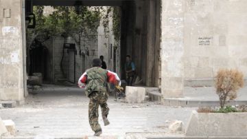 Un rebelde sirio corre para protegerse del fuego de un francotirador del ejército en Alepo, Siria.
