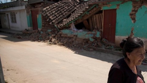 Una mujer camina frente a una casa que quedó destruida por el terremoto en San Marcos, al suroccidente de Guatemala.
