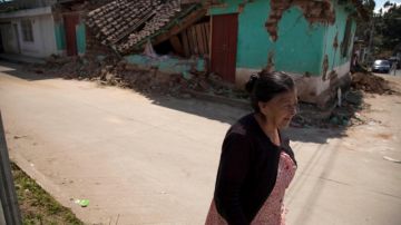 Una mujer camina frente a una casa que quedó destruida por el terremoto en San Marcos, al suroccidente de Guatemala.