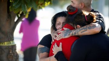 Tres mujeres y un hombre se consuelan afuera de la procesadora, en Fresno, donde ocurrió el tiroteo.