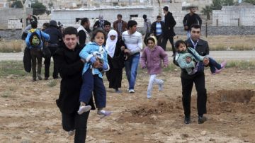 Varios sirios huyen de su país tras los enfrentamientos entre las tropas gubernamentales y los rebeldes en la región de Rasulayn, a unos cientos de metros del pueblo turco de Ceylanpinar, ayer.