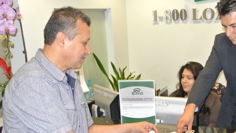 Oscar Rodríguez, de LoanMart, explica a Rodolfo Santana los términos de un préstamo sobre el título de su auto.