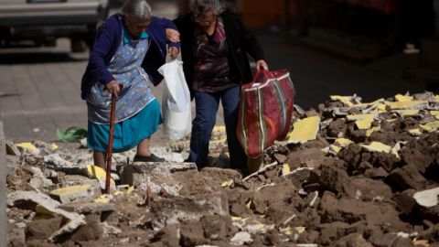 Dos personas caminan entre los escombros de edificios destruidos por el sismo, en San Pedro, Guatemala.