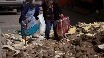 Dos personas caminan entre los escombros de edificios destruidos por el sismo, en San Pedro, Guatemala.