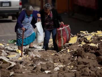 Dos personas caminan entre los escombros de edificios destruidos por el sismo, en San Pedro, Guatemala.