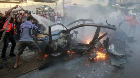 Varias personas intentan apagar los restos del coche en el que murió Ahmed Jabari, jefe del ala militar de Hamas en Gaza. El ejército israelí dijo que el asesinato del comandante militar de Hamas marca el inicio de una operación contra militantes de Gaza.