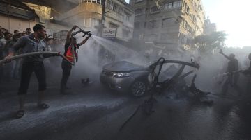 Los servicios de emergencia tratan de extinguir el coche destrozado que pertenecía a Ahmed Yabari, jefe del brazo armado de Hamás.