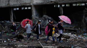 Niños palestinos atraviesan edificios destruidos por los cohetes ayer, día que miles regresaron a la escuela.