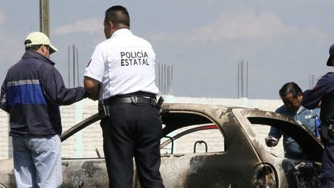 Policías estatales y peritos forenses recolectan evidencia en un vehículo abandonado en México.