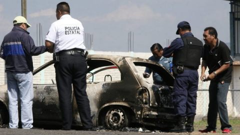 Policías estatales y peritos forenses recolectan evidencia en un vehículo abandonado en México.