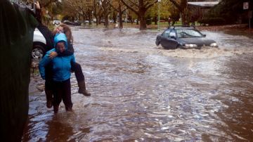 Unas personas caminan por una calle inundada en Sacramento.