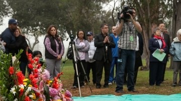 Phoebe Parker, derecha, coloca flores durante la ceremonia de entierro de restos cremados de muertos que no fueron reclamados.